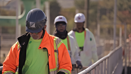 Three construction workers enter the job site to prepare for the day.