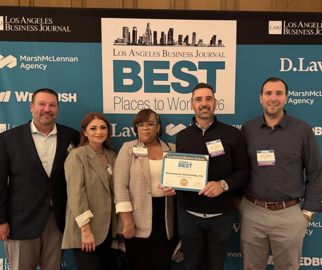 Five people hold a plaque in front of Best Places to Work backdrop